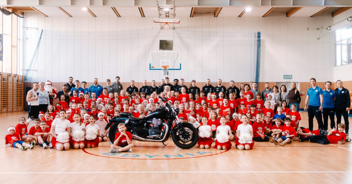 Zdjęcie grupowe uczestników mikołajkowego wydarzenia sportowego – dzieci w czerwonych koszulkach i święty Mikołaj.