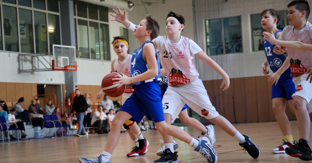 Akcja pod koszem – zawodnik w niebieskiej koszulce dynamicznie wbiega na pole trzech sekund, mijając obrońcę.