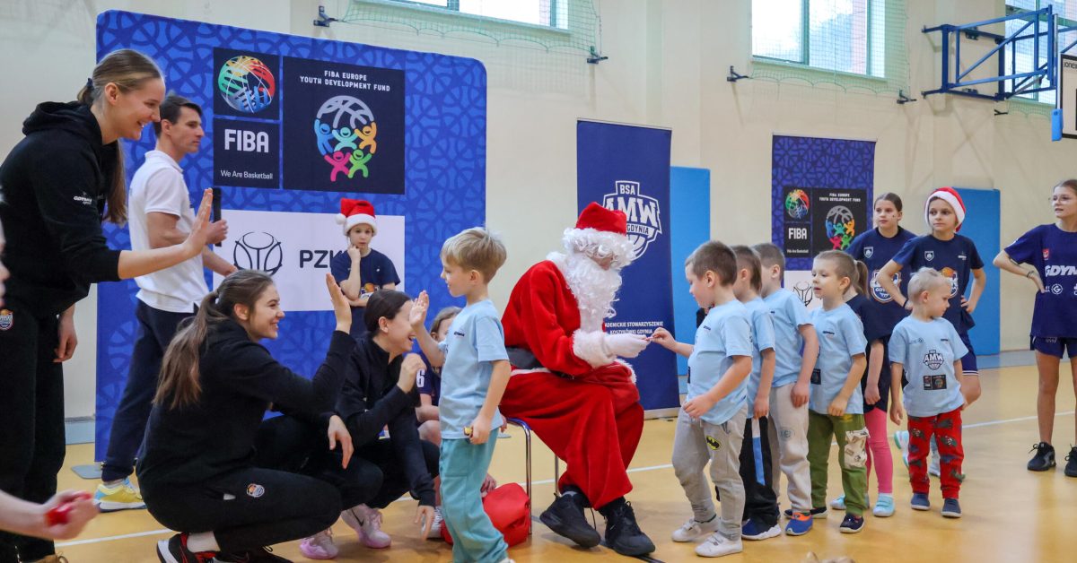 Dzieci witają się ze Świętym Mikołajem i zawodniczkami, na sali gimnastycznej.
